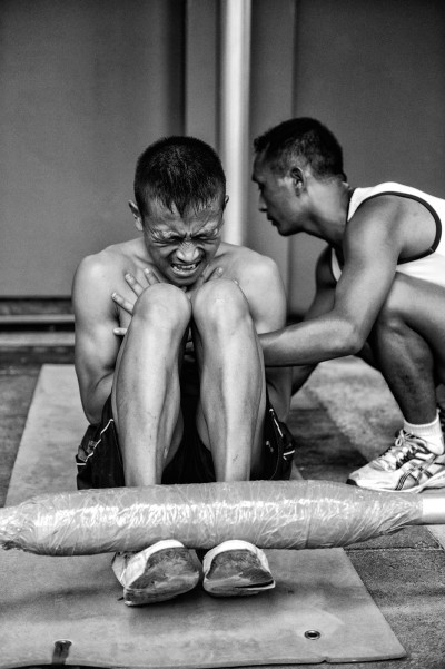 A young Nepali boy fighting through the required minimum of 70 sit-ups in two minutes, closely observed by a physical training instructor (PTI) who makes sure elbows are kept close to the body and the entire range of motion from ground to knees is completed